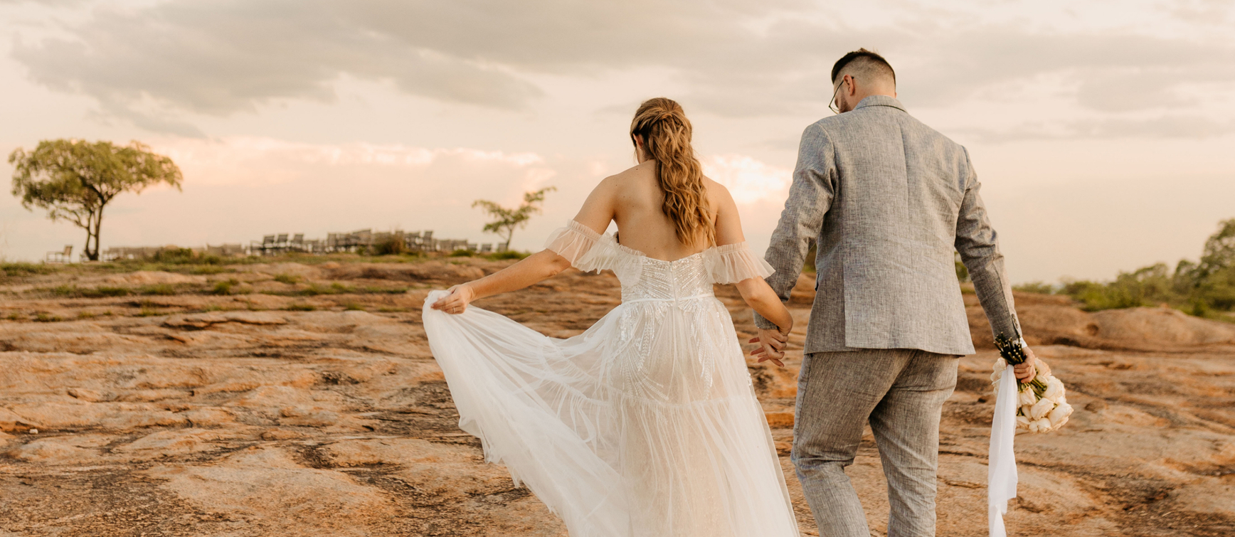 A newlywed couple walking hand in hand across the granite rocks at Mdluli Safari Lodge