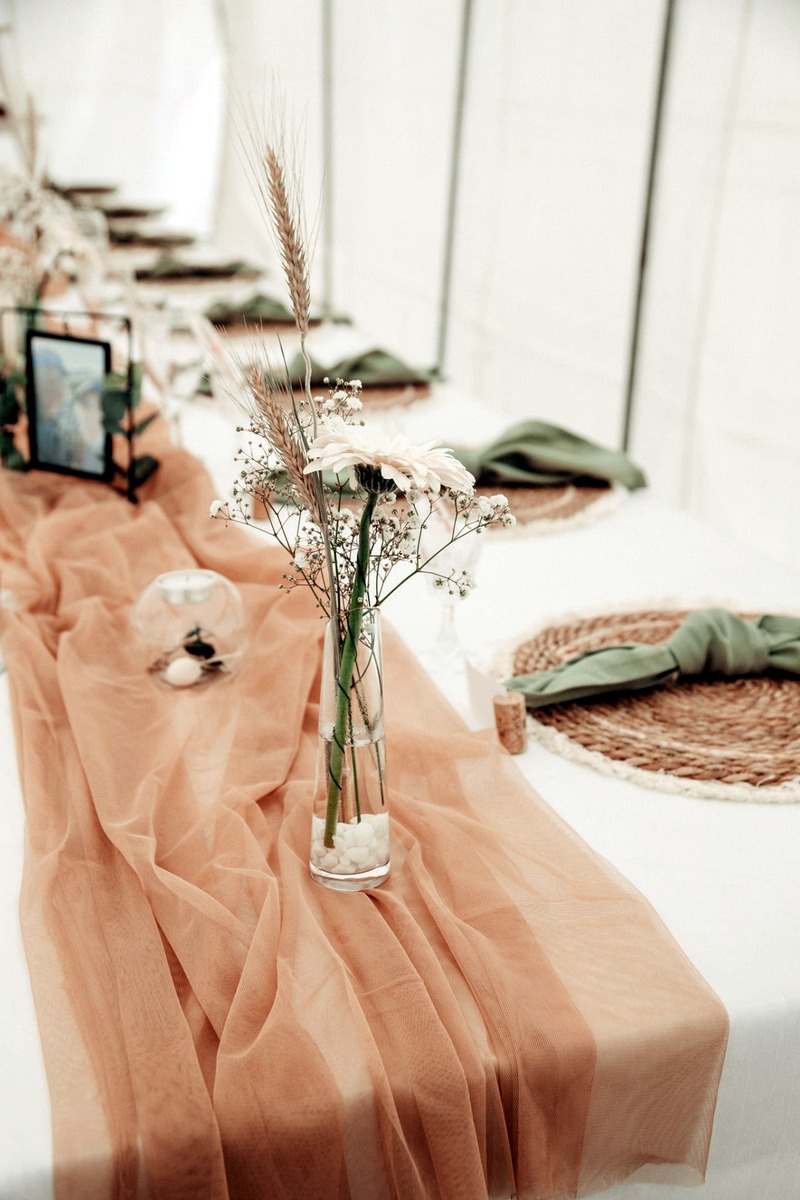 Elegant wedding table styling with soft peach fabric, dried flowers and woven placemats
